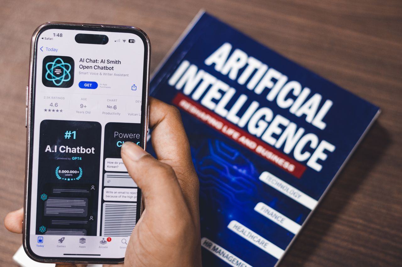 Services Smartphone displaying AI app with book on AI technology in background.